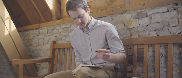 a Carroll University student sitting and writing on a notepad.